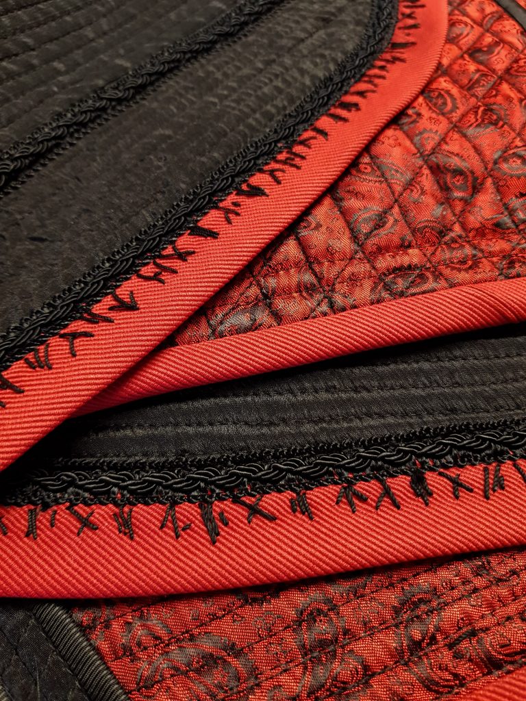 Black quilted jacket with red bias tape and black stitches