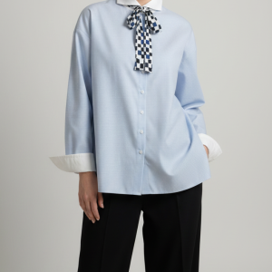 Close-up of a light blue button-up shirt featuring a structured white collar, smooth fabric, and refined cuff details for a modern, elevated look.