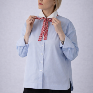 Model wearing a light blue long-sleeve button-up shirt with a contrast white collar, soft drape, and relaxed silhouette designed for effortless polish.