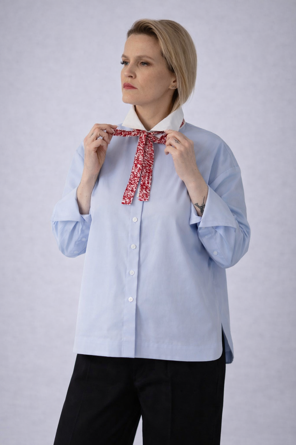 Model wearing a light blue long-sleeve button-up shirt with a contrast white collar, soft drape, and relaxed silhouette designed for effortless polish.