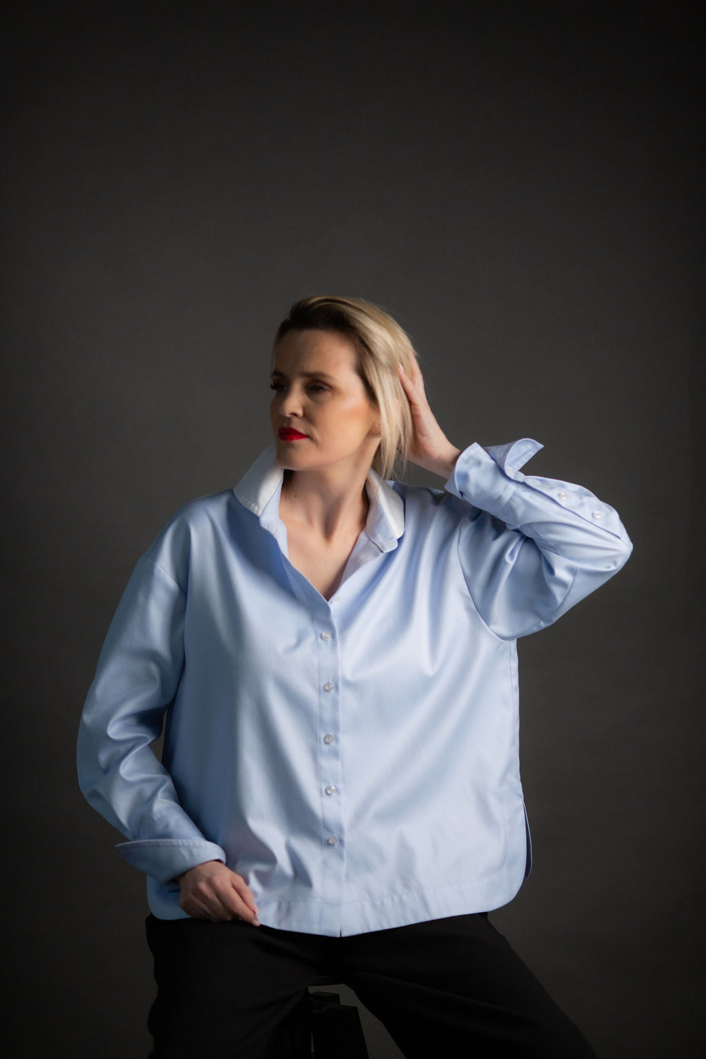 Model wearing a light blue long-sleeve button-up shirt with a contrast white collar, soft drape, and relaxed silhouette designed for effortless polish.