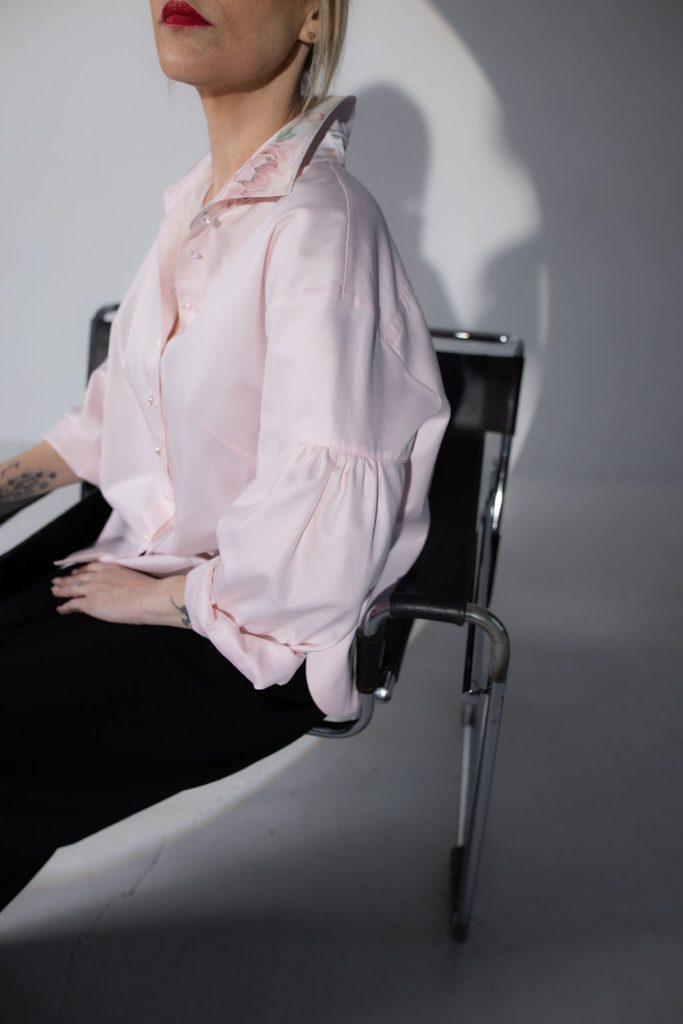 Model wearing a light pink button-up shirt featuring a sharp collar, smooth fabric, and an easy, relaxed silhouette for polished everyday wear.