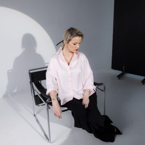 Model wearing a light pink button-up shirt featuring a sharp collar, smooth fabric, and an easy, relaxed silhouette for polished everyday wear.