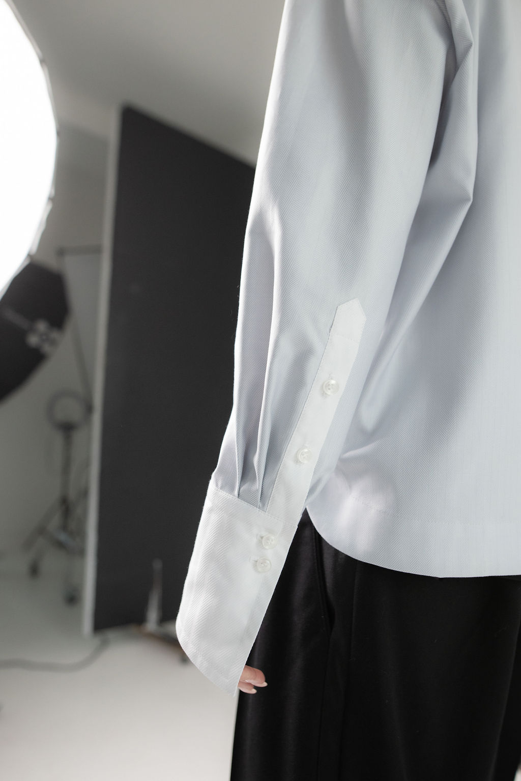Close-up of a light gray button-up shirt showcasing a structured collar, refined buttons, and fluid drape for a modern, elevated look.